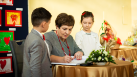 Podlaski Kurator Oświaty Pani Beata Pietruszka podpisuje się w księdze pamiątkowej w obecności dzieci.