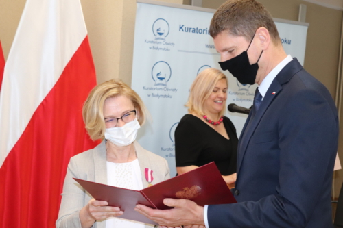 Wiceminister Edukacji i Nauki wręczający medal, w tle pracownik Kuratorium Oświaty w Białymstoku